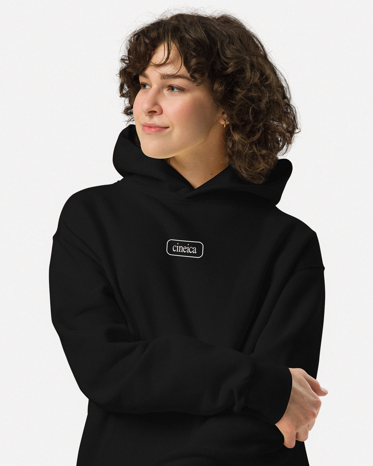 Photo of a woman wearing a black cineica "Blueprint Hoodie". The front design features a framed cineica logo.