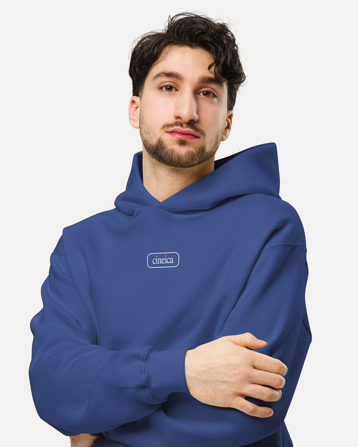 Photo of a man wearing a blue cineica "Blueprint Hoodie". The front design features a framed cineica logo.