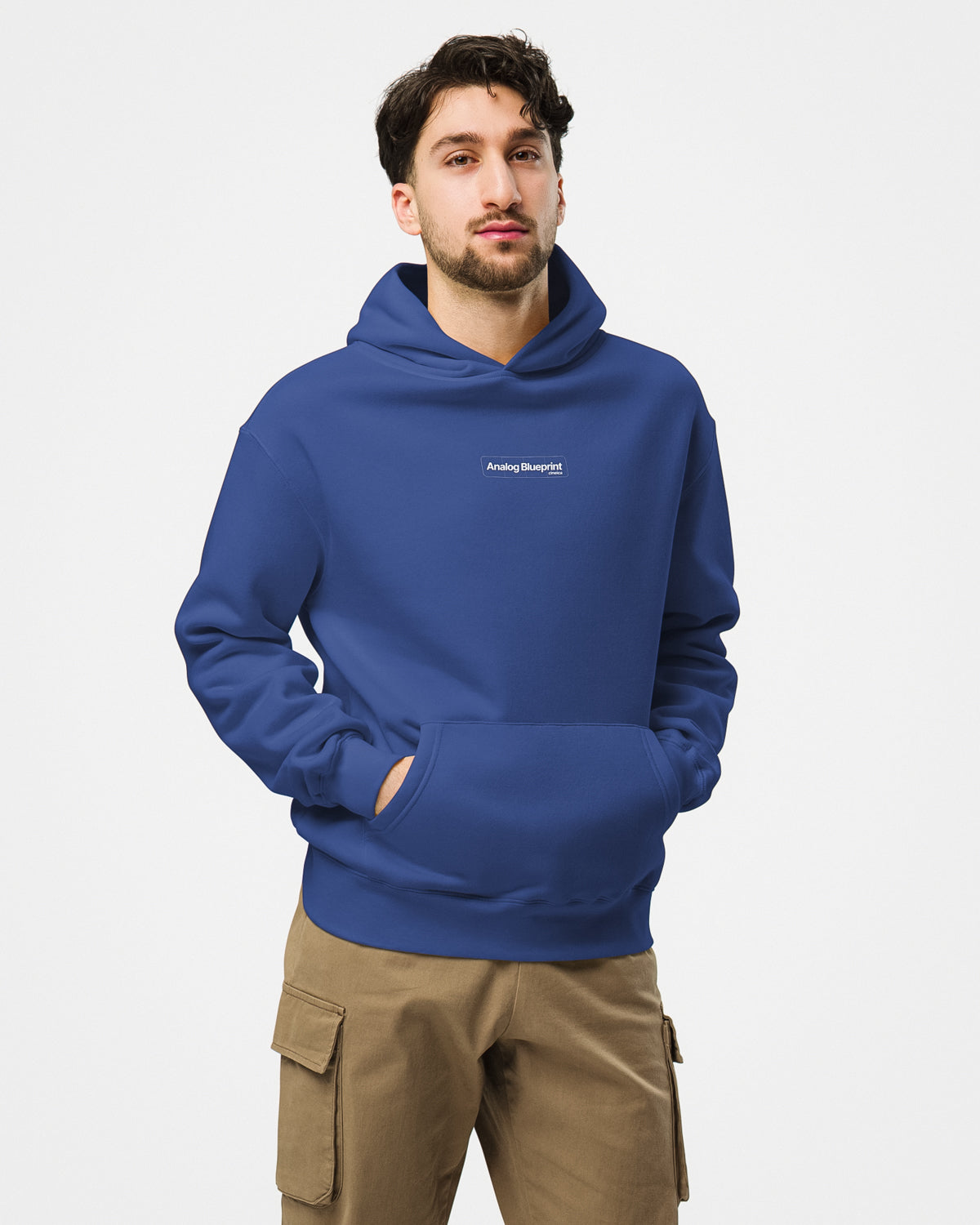 Front of a man wearing a blue hoodie with a white design featuring the text "Analog Blueprint", "cineica" centered on the chest.