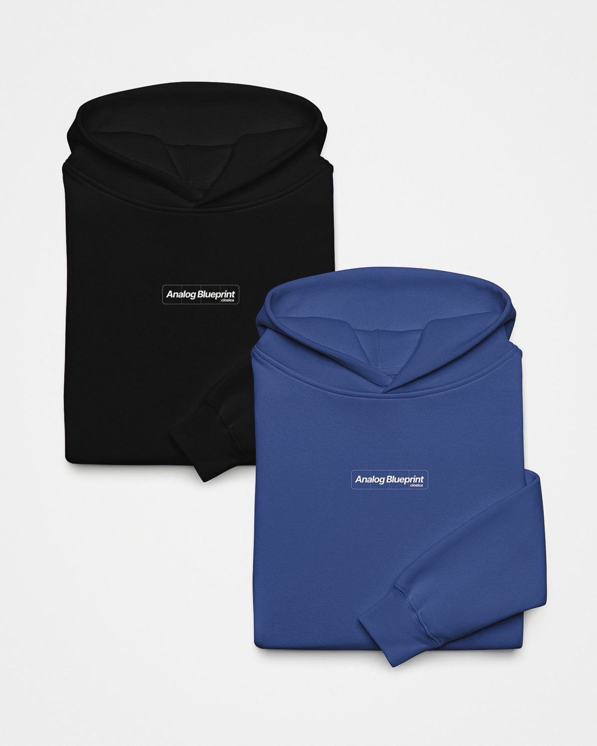 Fronts of a folded blue and black hoodie with a white design featuring the text "Analog Blueprint", "cineica" centered on the chest.