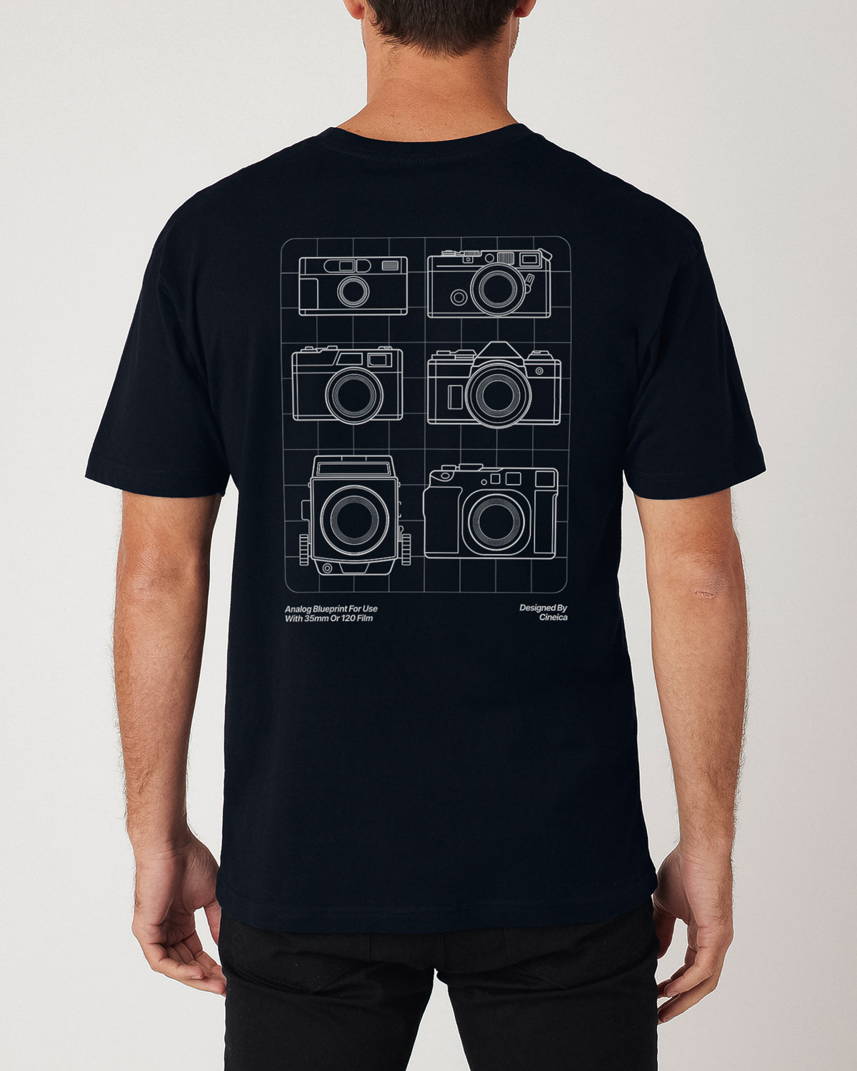 Back of a man wearing a navy t-shirt with a film photography camera design.