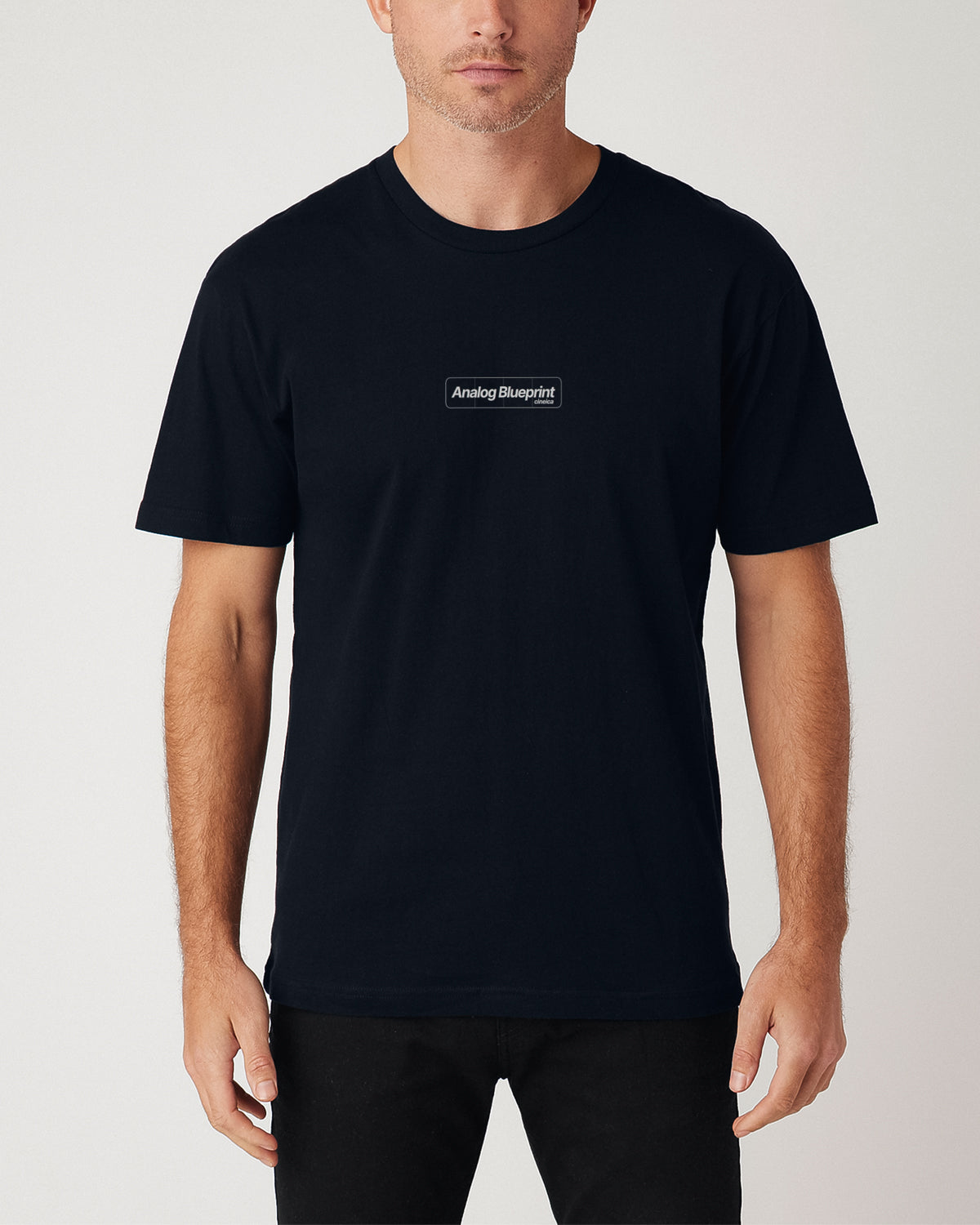 Front of a man wearing a navy t-shirt with text "Analog Blueprint", "cineica".