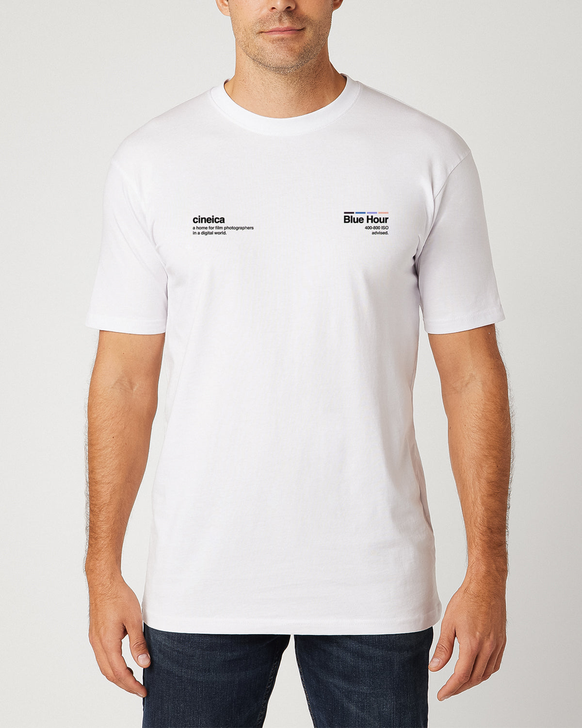 A man wearing a white t-shirt with text "cineica, a home for film photographers in a digital world." and "Blue Hour, 400-800 ISO advised.".