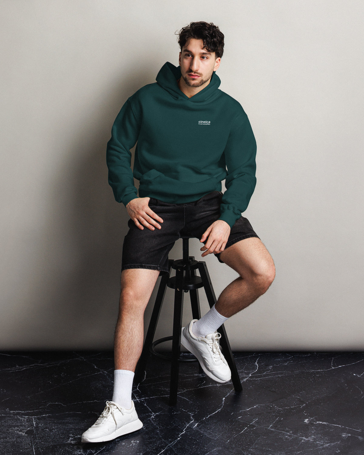 Photo of a man wearing a green cineica "FOUR HUNDRED" hoodie.