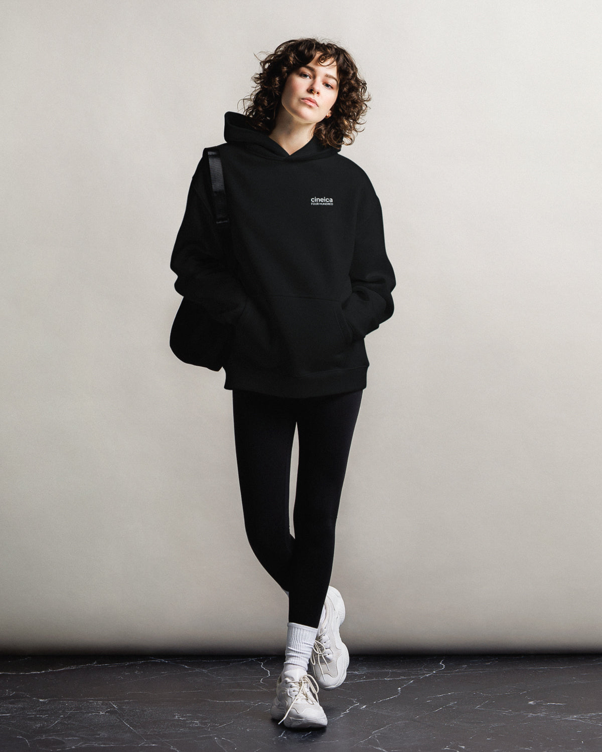 Photo of a woman wearing a black cineica "FOUR HUNDRED" hoodie.
