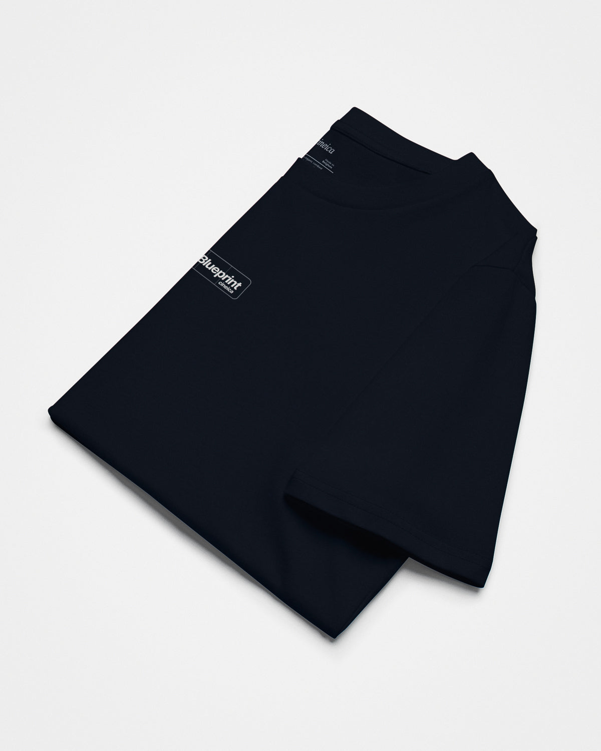 Front of a folded navy t-shirt with text "Analog Blueprint", "cineica".
