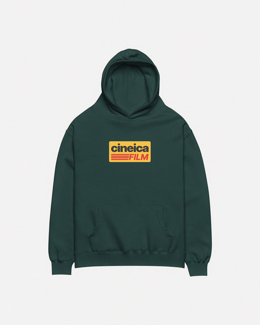 Photo of a green cineica hoodie front. The design features a yellow graphic with black and red text in a vintage style, the text states "cineica FILM".